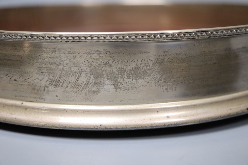 A large modern silver mounted table coaster, 25.7cm and two other modern wine coasters, one silver.